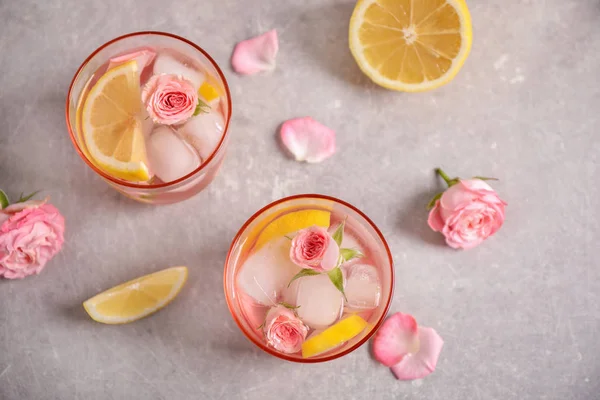 Tasty refreshing lemon drink with roses on light grey table, flat lay — Stock Photo, Image