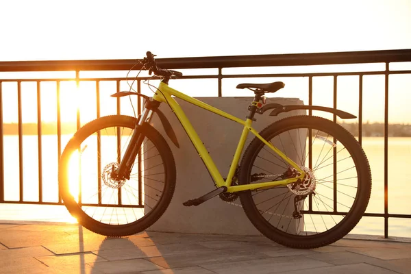 Bicyclette jaune garée près de la rampe sur le front de mer de la ville au coucher du soleil — Photo