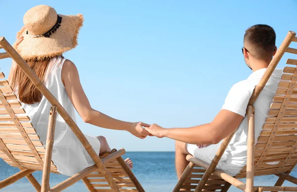 年轻夫妇在海滩上的躺椅上放松 — 图库照片