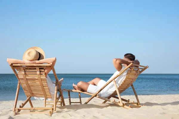젊은 부부는 해변에서 갑판 의자에서 휴식 — 스톡 사진