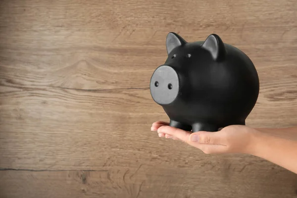 Vrouw houden Piggy Bank op houten achtergrond, close-up weergeven. Ruimte voor tekst — Stockfoto