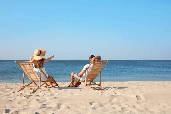 年轻夫妇在海滩上的躺椅上放松 — 图库照片