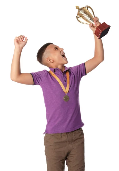 Menino feliz com copo de ouro vencedor e medalha no fundo branco — Fotografia de Stock