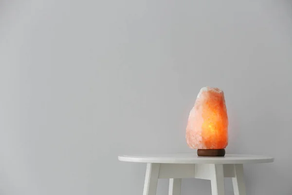 Himalayan salt lamp on table against white background. Space for text