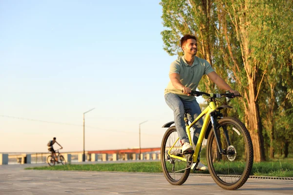 Красивий молодий чоловік їде на велосипеді на міській набережній — стокове фото