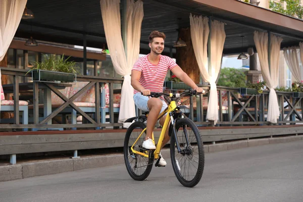 Bonito jovem andando de bicicleta na rua da cidade — Fotografia de Stock