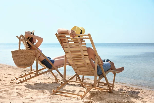 Junges Paar entspannt in Liegestühlen am Strand — Stockfoto