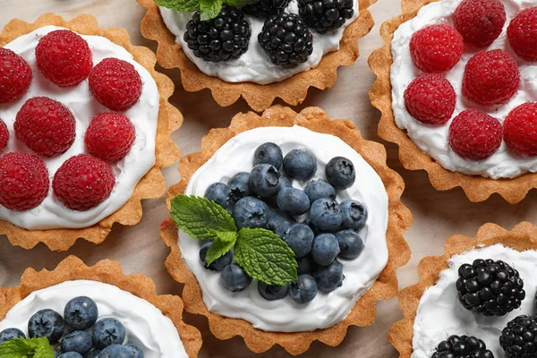 Many different berry tarts on table, top view. Delicious pastries — Stock Photo, Image