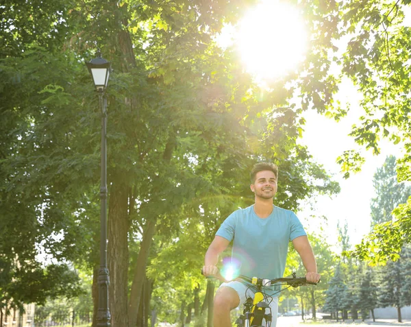 Красивий молодий чоловік їде на велосипеді на міській вулиці, низький кут зору — стокове фото