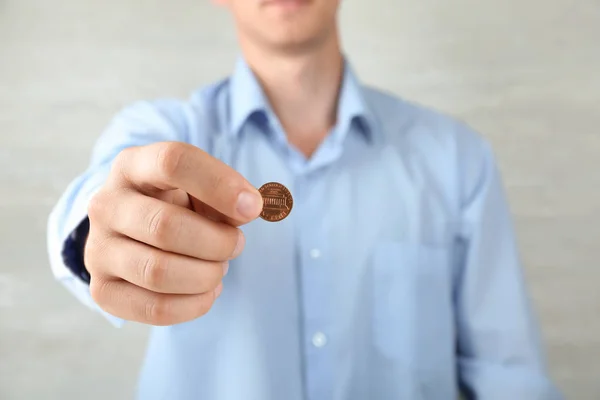 Hombre sosteniendo moneda sobre fondo gris, vista de cerca — Foto de Stock