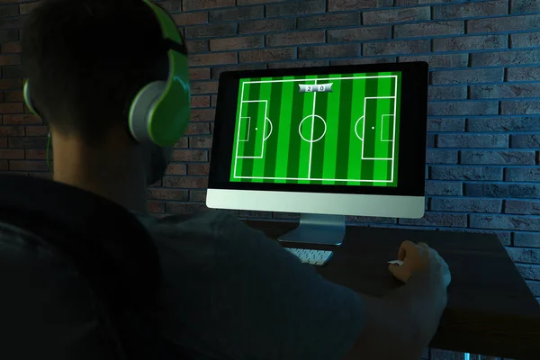 Hombre con auriculares jugando videojuego en la mesa en la habitación oscura — Foto de Stock