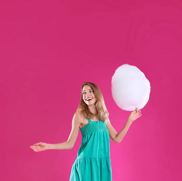 Gelukkige jonge vrouw met suikerspin op roze achtergrond — Stockfoto