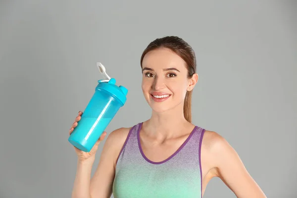 Atletische jonge vrouw met proteïne Shake op lichtgrijze achtergrond — Stockfoto