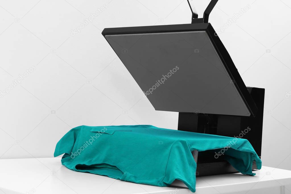 Heat press machine with t-shirt on table against light background