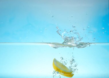 Mavi arka plan karşı limon dilimleri ile su. Ferahlatıcı içecek