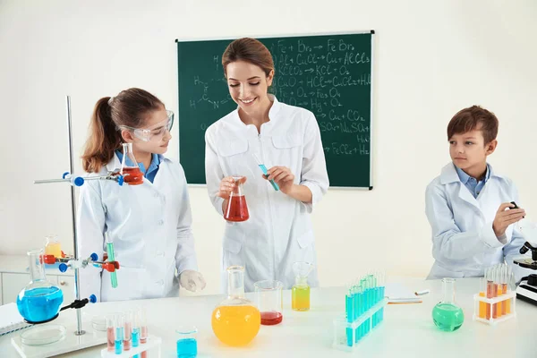 Professora com alunos fazendo experiência em aula de química — Fotografia de Stock