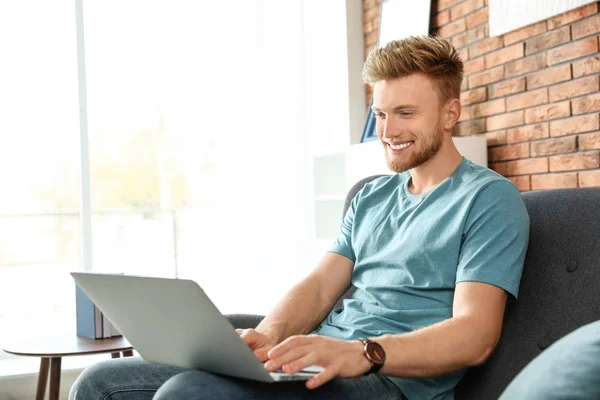 Junger Mann benutzt Laptop im Wohnzimmer — Stockfoto