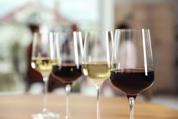 Glazen met verschillende wijnen op tafel tegen onscherpe achtergrond — Stockfoto