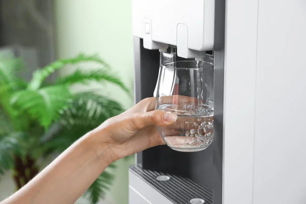Kobieta napełniania szkła z chłodnicy wody w pomieszczeniu, zbliżenie. Orzeźwiający napój — Zdjęcie stockowe