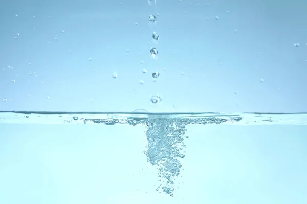 Friskt vatten med bubblor mot blå bakgrund — Stockfoto