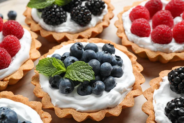 Many different berry tarts on table, closeup. Delicious pastries — Stock Photo, Image