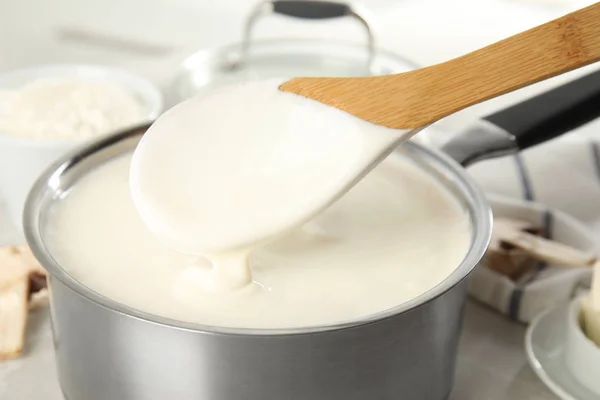 Spoon and pan with delicious creamy sauce, closeup view — Stock Photo, Image