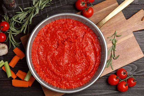 Siyah ahşap masa üzerinde lezzetli domates sosu ile Düz yatıyordu kompozisyon — Stok fotoğraf