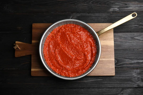 Heerlijke tomatensaus in pan op zwarte houten tafel, Top View — Stockfoto