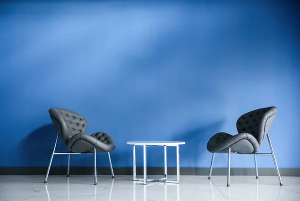 Άνετες πολυθρόνες και μεταλλικό τραπέζι κοντά στον μπλε τοίχο. Μοντέρνο εσωτερικό δωμάτιο — Φωτογραφία Αρχείου