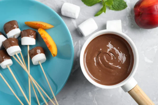 Fonduetopf mit Vollmilchschokolade und Marshmallows auf Marmortisch, Draufsicht — Stockfoto