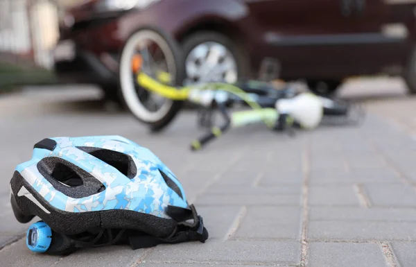Fallen bicycle after car accident outdoors, focus on helmet — Stock Photo, Image