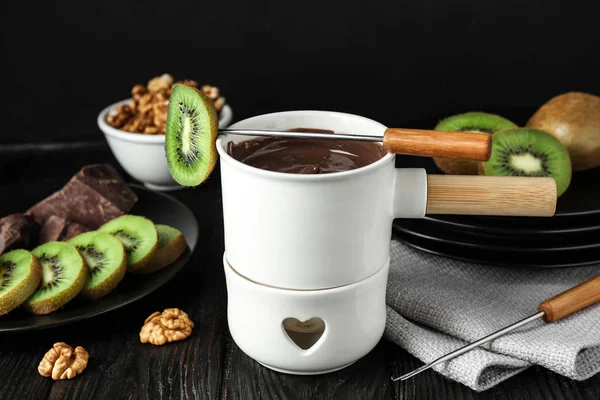 Fondue olla con chocolate y kiwis sobre mesa de madera negra — Foto de Stock