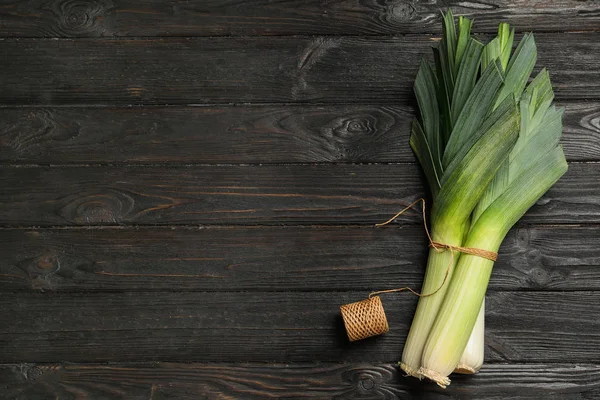 Fresh raw leeks on black wooden table, flat lay with space for text. Ripe onion — Stock Photo, Image