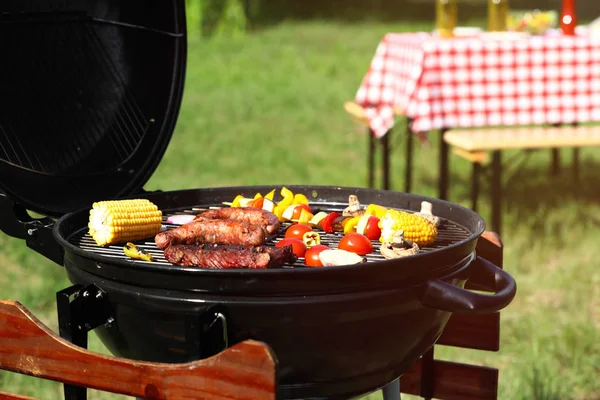 Смачний стейк, сосиски та овочі на сучасному грилі барбекю на відкритому повітрі — стокове фото