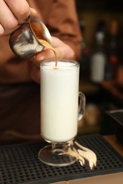 Barista tezgahta buğulanmış süt kahve ekleme, closeup görünümü