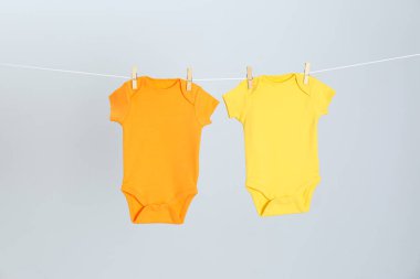 Açık gri arka plan karşı giysi hattı üzerinde asılı farklı bebek onesies. Çamaşır günü
