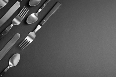Siyah arka plan üzerinde yeni metal çatal seti, metin için boşluk ile düz yatıyordu