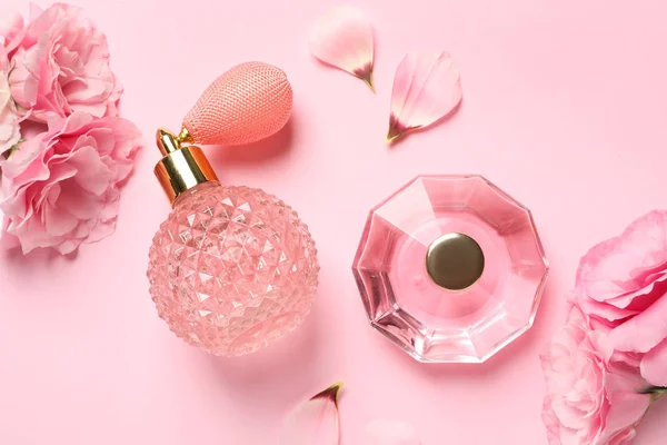 Lapos feküdt kompozíció parfümös palackok és virágok világos rózsaszín háttér — Stock Fotó