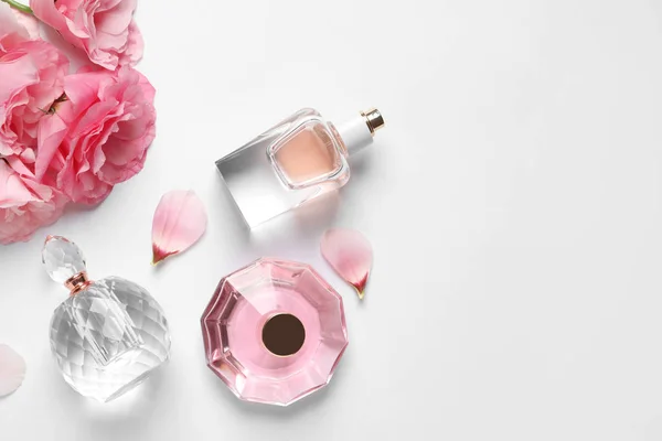 Beyaz arka planda farklı parfüm şişeleri ve çiçekler, üst görünüm — Stok fotoğraf