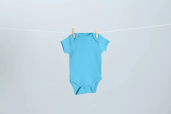 Bonito bebê onesie pendurado na linha de roupas contra fundo cinza claro. Dia de lavandaria — Fotografia de Stock