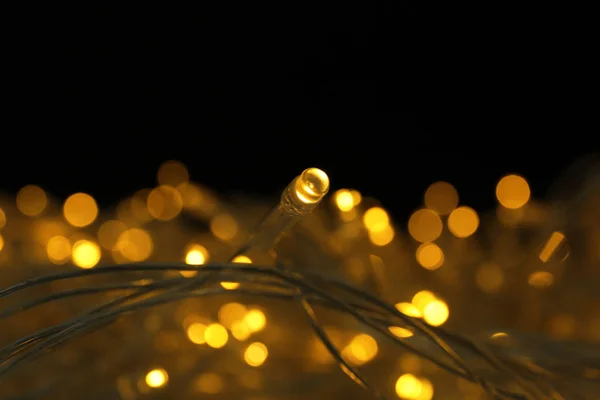 Zářící vánoční světla na tmavém pozadí, detailní záběr — Stock fotografie