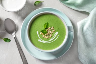 Cup of healthy green soup with fresh spinach served on light table, flat lay clipart