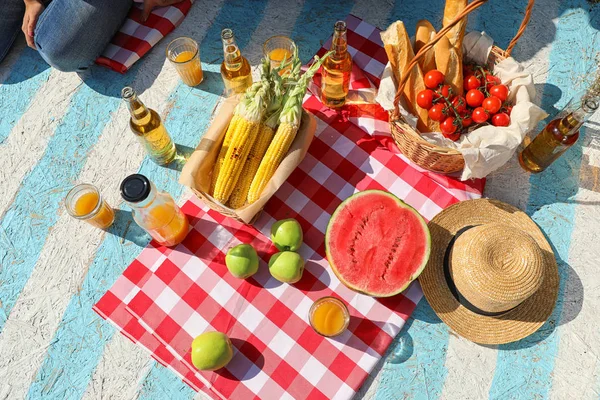 Strohhut und verschiedene Produkte für das Sommerpicknick auf karierter Decke, flache Lage — Stockfoto