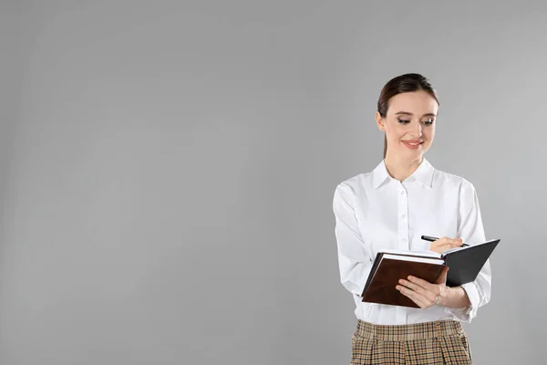 Portret van een jonge vrouwelijke leraar op een grijze achtergrond. Ruimte voor tekst — Stockfoto