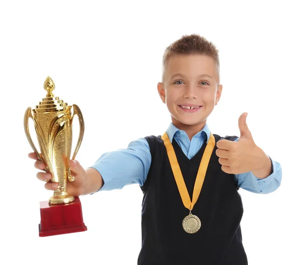 Ευτυχισμένο αγόρι με σχολική στολή με χρυσό κύπελλο και μετάλλιο απομονωμένο σε λευκό — Φωτογραφία Αρχείου
