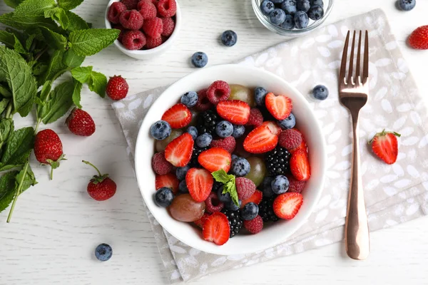 Salada de frutas saborosa fresca na mesa de madeira branca, flat lay — Fotografia de Stock