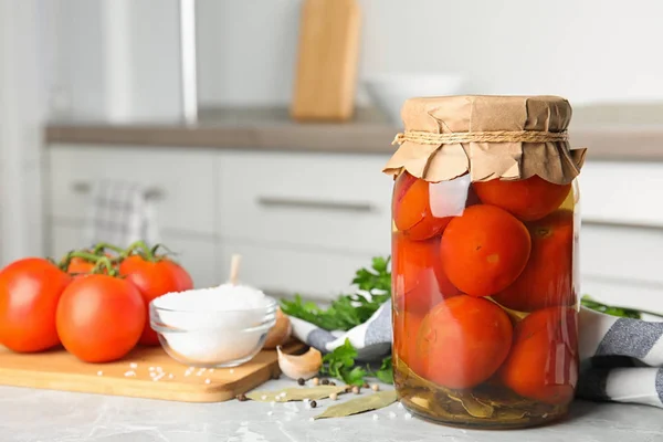 Tarro con tomates en escabeche y verduras en la mesa gris en la cocina. Espacio para texto — Foto de Stock