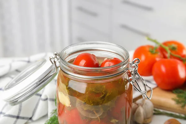 Tomates en escabeche en frasco de vidrio y productos en la mesa de la cocina, vista de primer plano — Foto de Stock