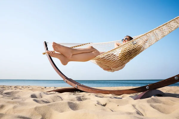 Giovane donna rilassante in amaca sulla spiaggia — Foto Stock