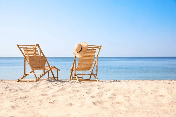 Trä däck stolar på sandstrand nära havet — Stockfoto